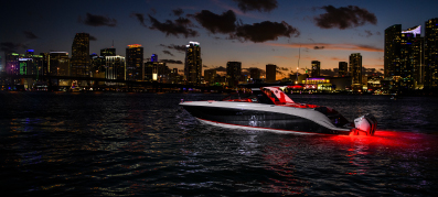 View of a Sea Ray boat cruising at night with a city skyline background 