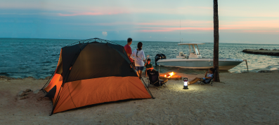 Tent on a beach with a boat in the background at night