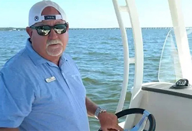 man with hat on standing at helm of a boat