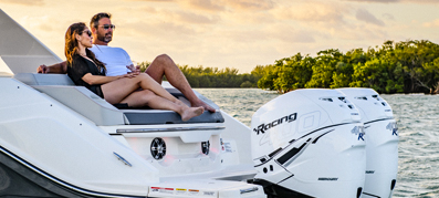 Couple sitting on the boat with sunset on a background